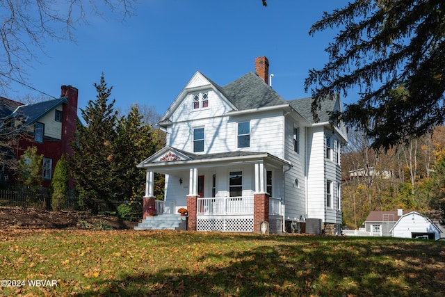 victorian-style house with central air condition unit, a front lawn, and covered porch