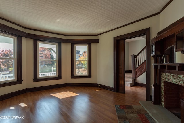 spare room featuring a wealth of natural light, crown molding, and dark hardwood / wood-style floors