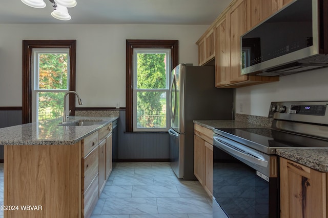 kitchen featuring a wealth of natural light, sink, appliances with stainless steel finishes, and an island with sink