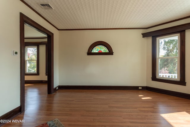 empty room with plenty of natural light, dark wood-type flooring, and ornamental molding