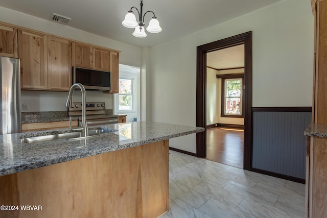 kitchen with stainless steel appliances, hanging light fixtures, a healthy amount of sunlight, and dark stone countertops