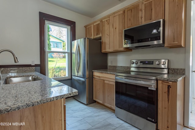 kitchen with light stone counters, sink, and appliances with stainless steel finishes