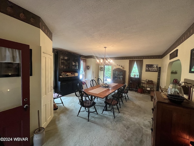 carpeted dining space with a textured ceiling and an inviting chandelier