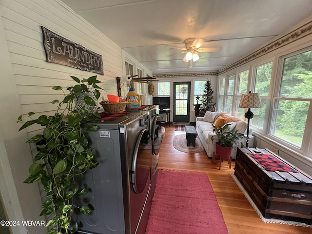 interior space featuring washer and dryer, light hardwood / wood-style floors, ceiling fan, and wooden walls