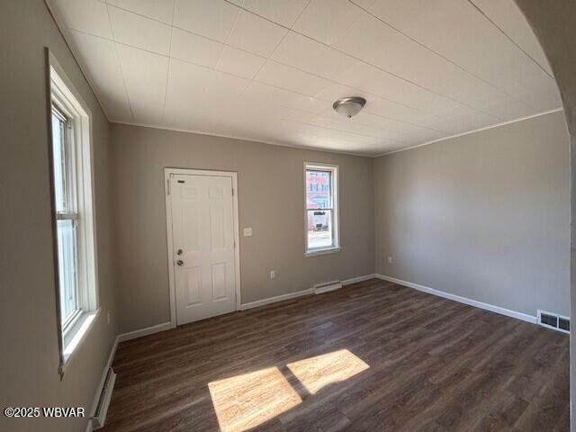 spare room featuring dark wood-type flooring, baseboards, visible vents, and a baseboard radiator