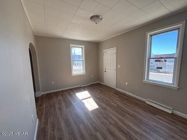 unfurnished room featuring arched walkways, visible vents, baseboards, and wood finished floors