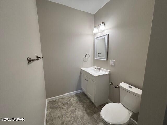 half bath featuring vanity, toilet, and baseboards