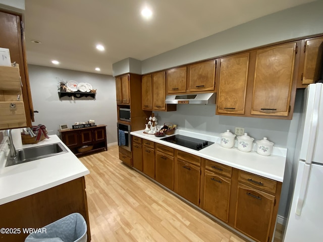 699 James St, Lock Haven, PA 17745 - kitchen with appliances with stainless steel finishes, under cabinet range hood, a sink, light wood finished floors, and brown cabinetry