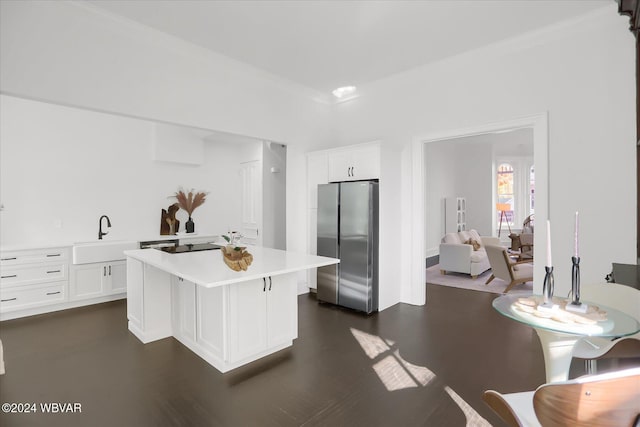 kitchen featuring a kitchen breakfast bar, a kitchen island, sink, white cabinetry, and stainless steel refrigerator