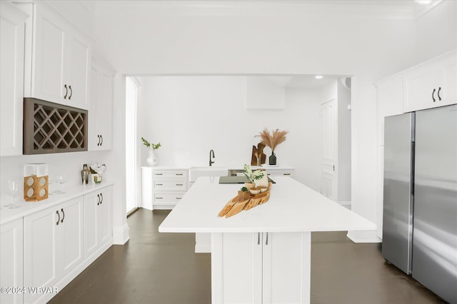 kitchen with white cabinets, a kitchen breakfast bar, stainless steel refrigerator, and sink