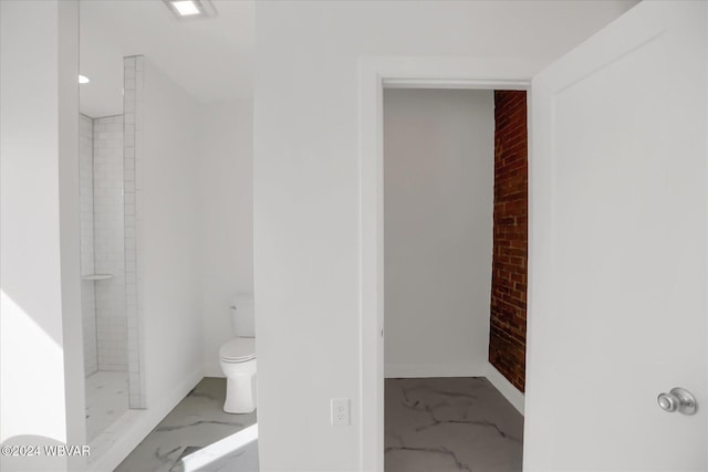 bathroom featuring toilet and tiled shower