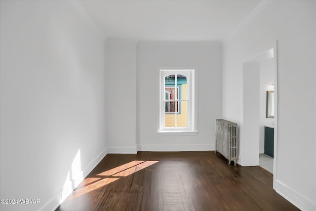 empty room with dark hardwood / wood-style flooring, radiator, and crown molding