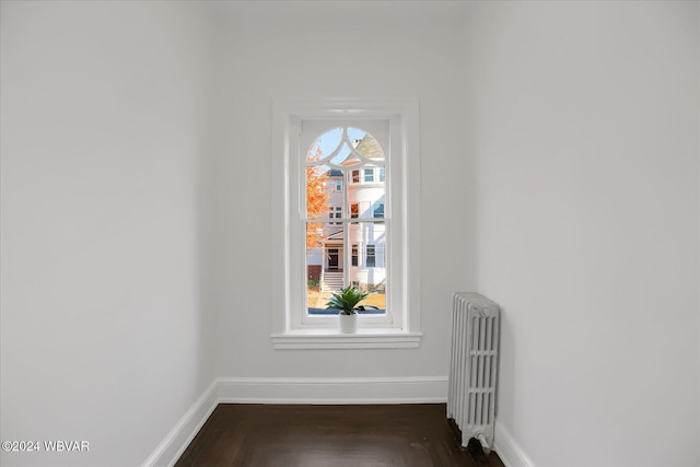 spare room featuring dark hardwood / wood-style flooring and radiator