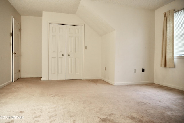 bonus room with lofted ceiling, light colored carpet, and a textured ceiling