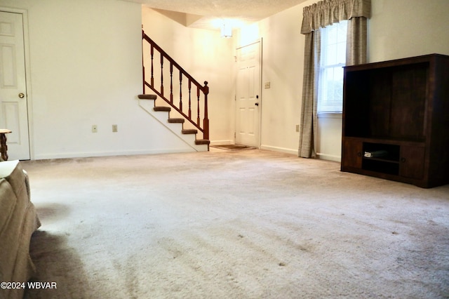 unfurnished living room with a textured ceiling and light colored carpet