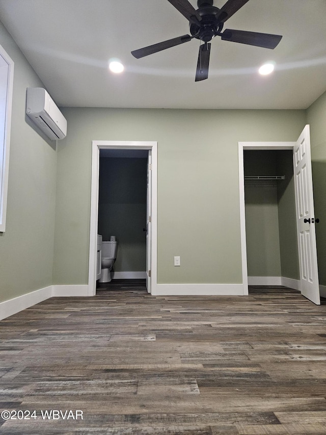 unfurnished bedroom with ceiling fan, dark hardwood / wood-style flooring, a wall unit AC, and ensuite bath