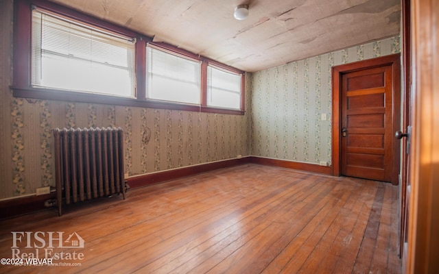 unfurnished room featuring radiator heating unit and hardwood / wood-style flooring