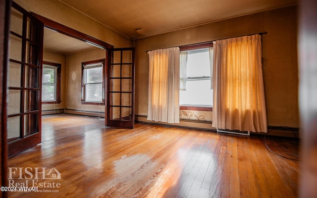 spare room with french doors, hardwood / wood-style flooring, and a baseboard heating unit