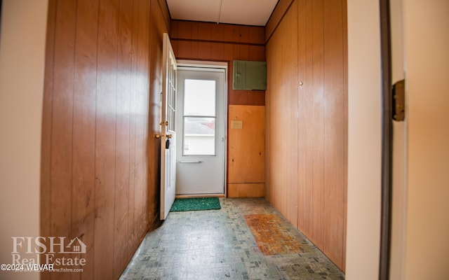 doorway to outside with wood walls