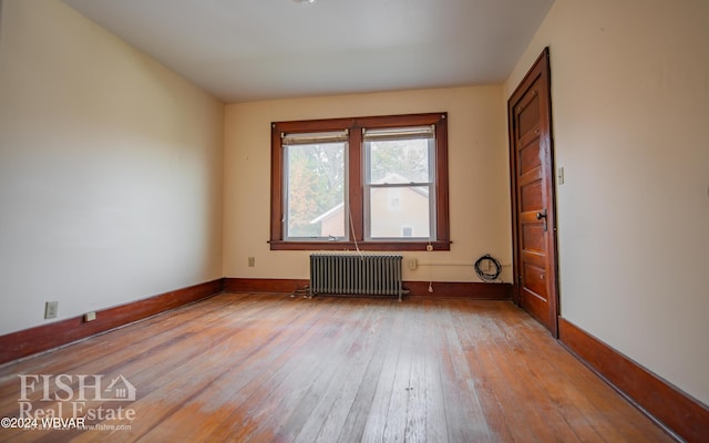 unfurnished room with radiator and light wood-type flooring