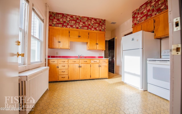 kitchen with white appliances, radiator heating unit, and sink