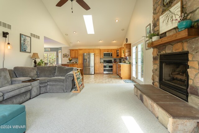 living room featuring plenty of natural light, ceiling fan, a stone fireplace, and high vaulted ceiling