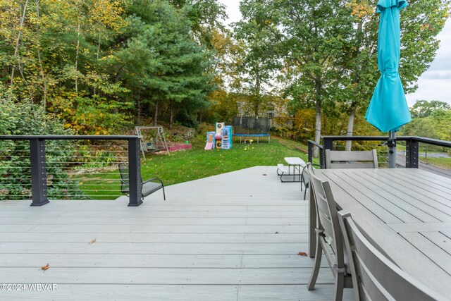 wooden terrace featuring a playground, a yard, and a trampoline