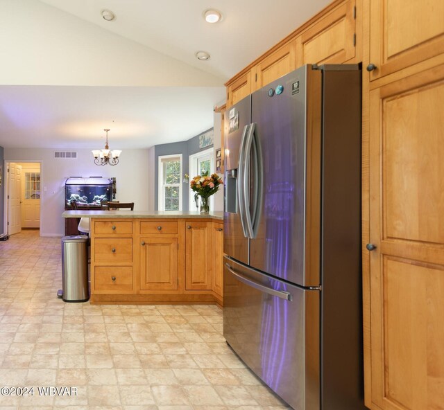 kitchen featuring kitchen peninsula, stainless steel refrigerator with ice dispenser, pendant lighting, a chandelier, and lofted ceiling