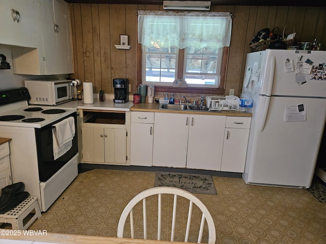 225 Pickwick St, Mill Hall, PA 17751 - kitchen with a sink, white cabinetry, wood walls, white appliances, and light countertops