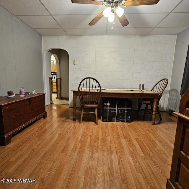 dining room featuring a paneled ceiling, ceiling fan, light wood-type flooring, and arched walkways