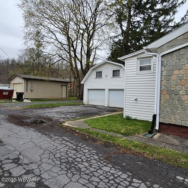 view of side of property featuring aphalt driveway and an outdoor structure