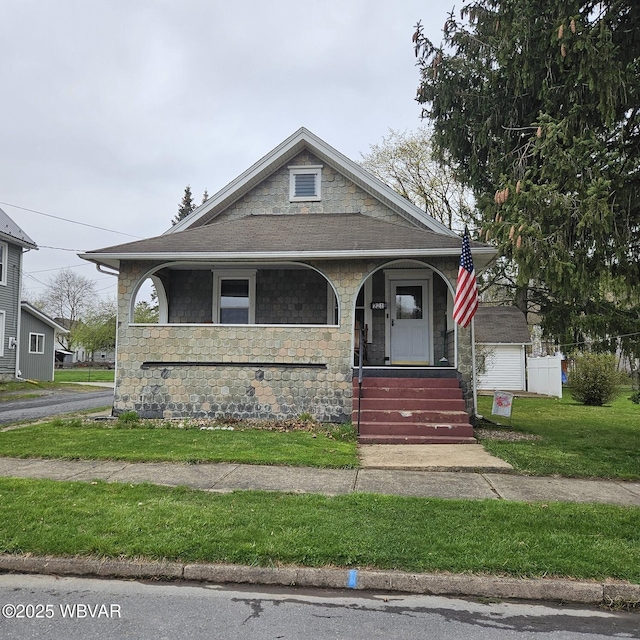 bungalow-style home with a porch, stone siding, and a front lawn