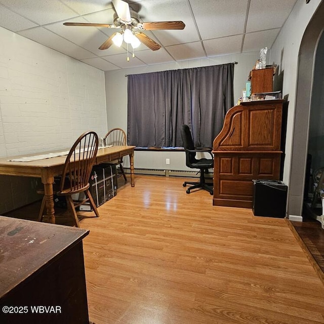 office space featuring arched walkways, a drop ceiling, and light wood-type flooring