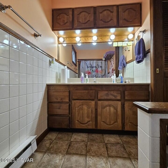 full bathroom featuring a baseboard radiator, vanity, and tile walls