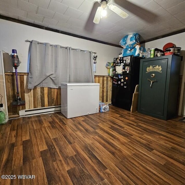 washroom featuring ceiling fan, a wainscoted wall, baseboard heating, wood finished floors, and wood walls