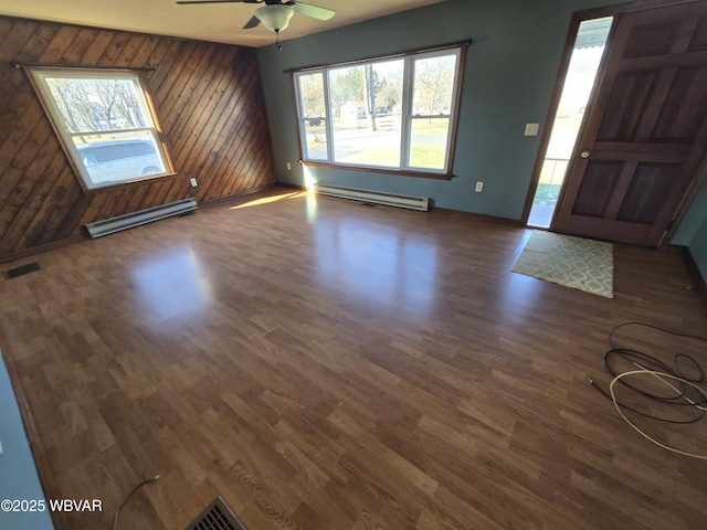 foyer entrance with dark wood-type flooring, baseboard heating, and wooden walls