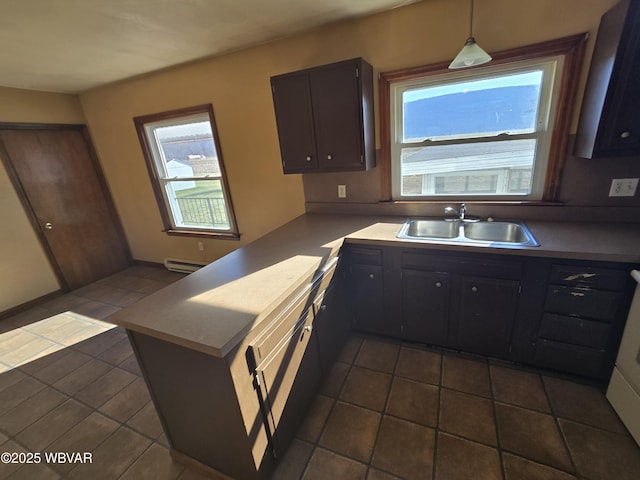 kitchen with dark tile patterned flooring, decorative light fixtures, sink, kitchen peninsula, and dark brown cabinets