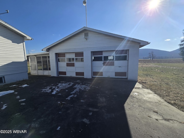 view of front of home featuring a garage, a sunroom, a mountain view, and an outdoor structure