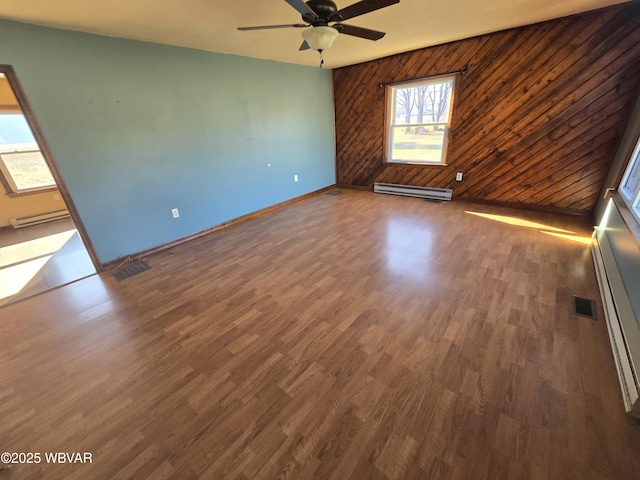 empty room featuring ceiling fan, baseboard heating, and dark hardwood / wood-style flooring