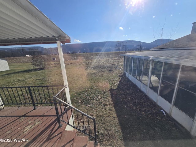 view of yard with a rural view, a sunroom, and a mountain view