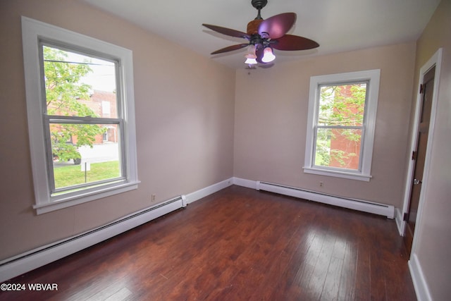 unfurnished room with baseboard heating, a wealth of natural light, and dark wood-type flooring