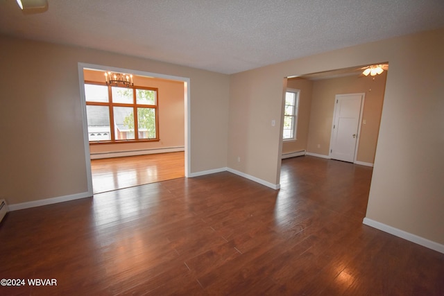 empty room featuring baseboard heating, a wealth of natural light, and dark wood-type flooring