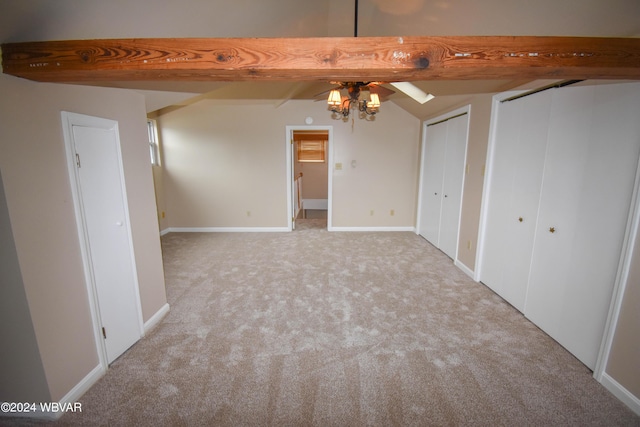 interior space featuring beamed ceiling, light carpet, and ceiling fan