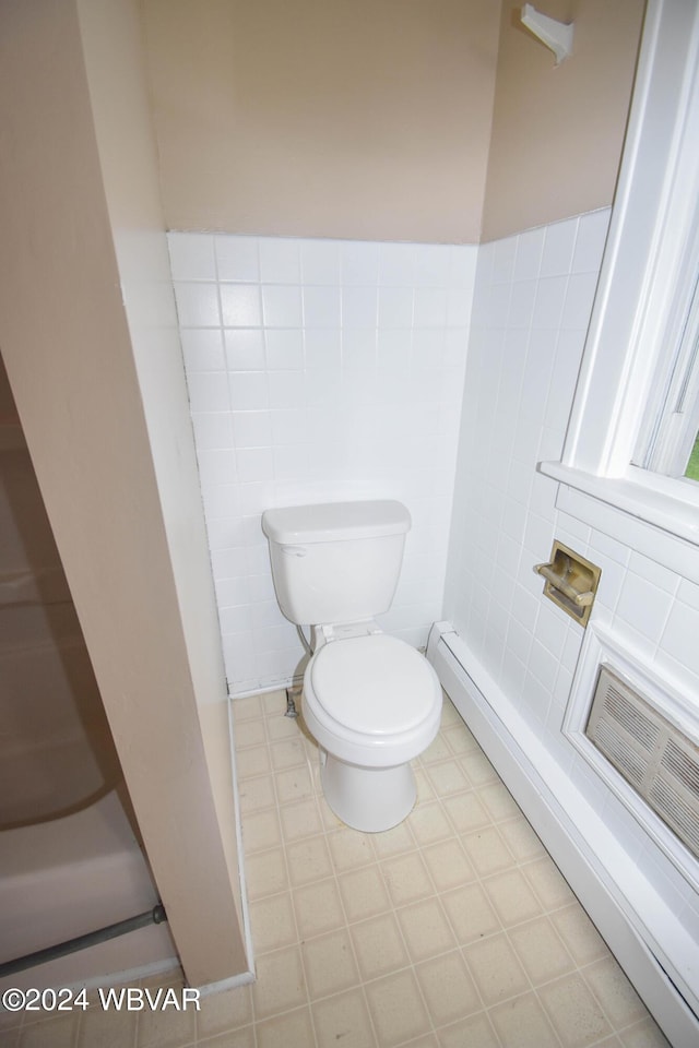 bathroom with a baseboard radiator, tile walls, and toilet