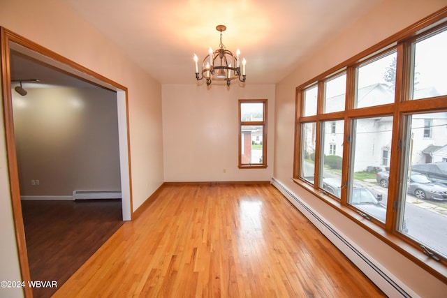 spare room featuring light hardwood / wood-style flooring, a chandelier, and a baseboard heating unit