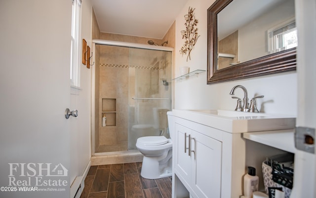 bathroom with a baseboard radiator, vanity, toilet, and a shower with door