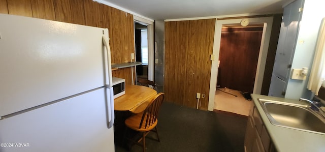 kitchen with wood walls, sink, and white appliances