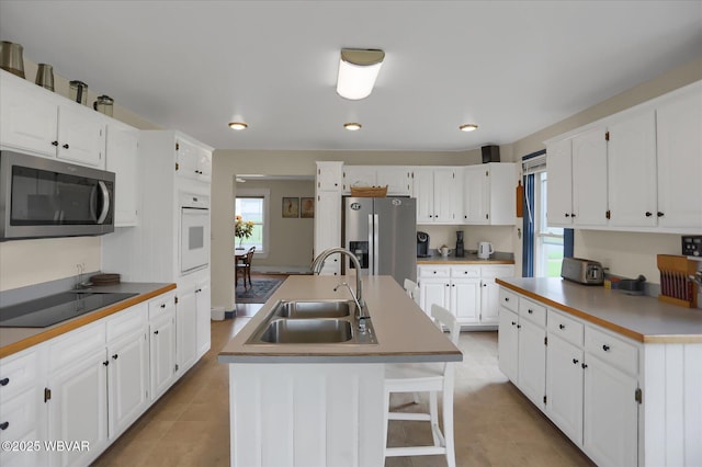 kitchen with stainless steel appliances, a sink, plenty of natural light, and a center island with sink