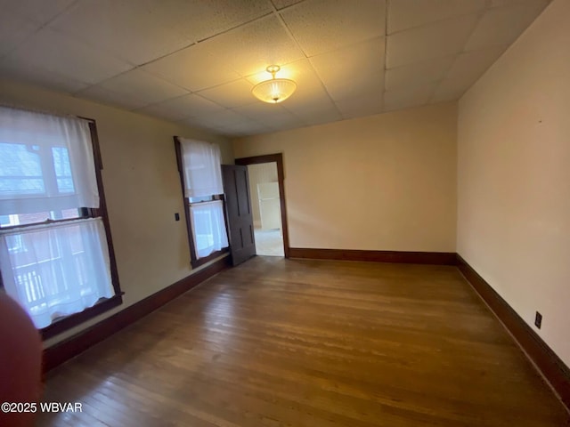 spare room featuring baseboards, wood finished floors, and a paneled ceiling