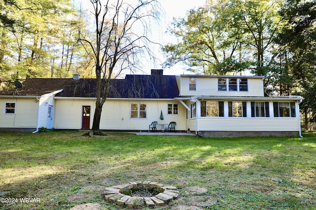 rear view of property featuring a lawn, a sunroom, and a patio